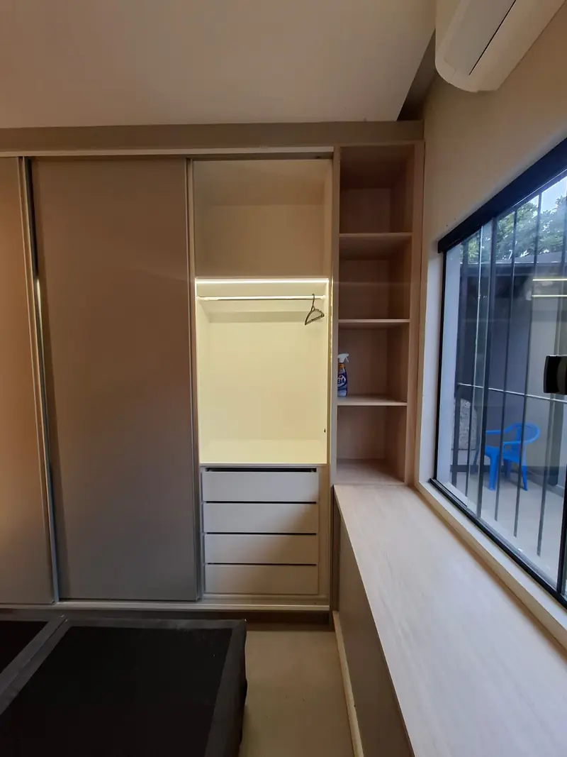 Closet com gaveteiro interno e cabideiro junto à janela