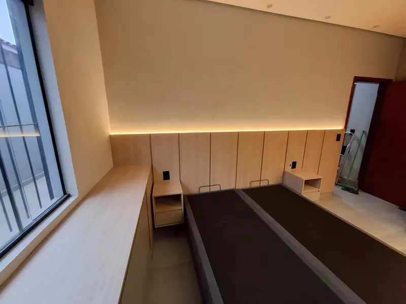 Dormitório planejado com painel ripado iluminado e cabeceira