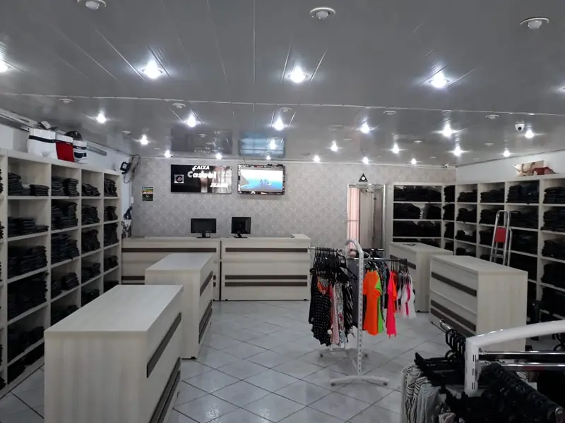 Loja de roupas com expositores de parede e mesas de exposição