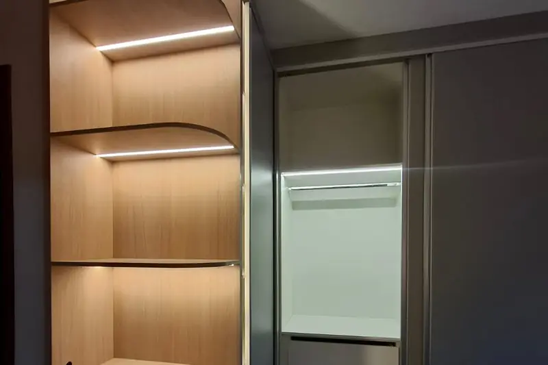 Closet planejado em madeira clara com prateleiras abertas e ilha central